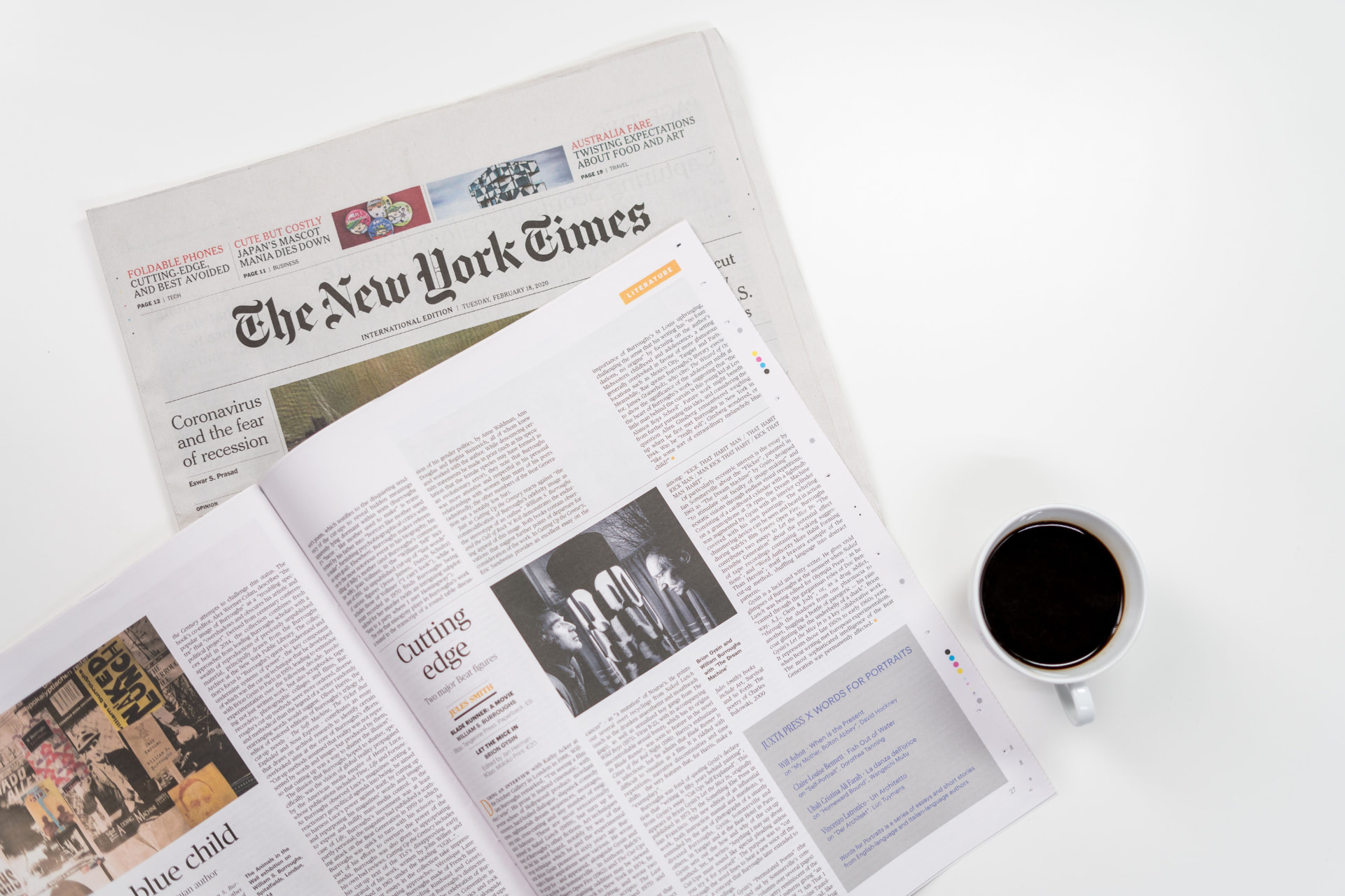 Newspapers and a cup of coffee on a white table
